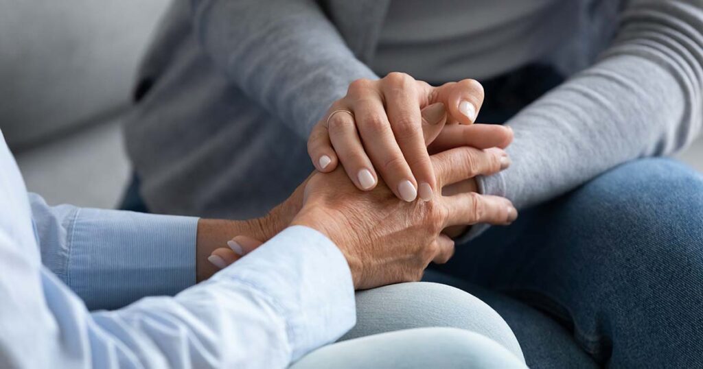 Healing from a traumatic death, two female hands holding while sitting