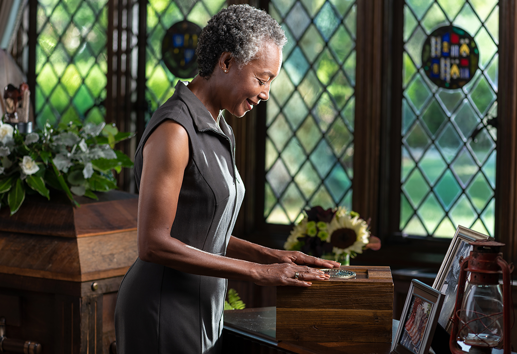 woman thoughtfully laying hands over an urn at a funeral