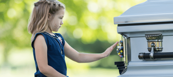 girl touching medallion on casket