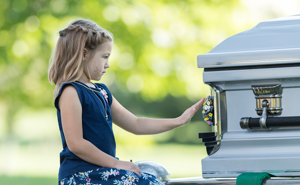 girl touching medallion on casket