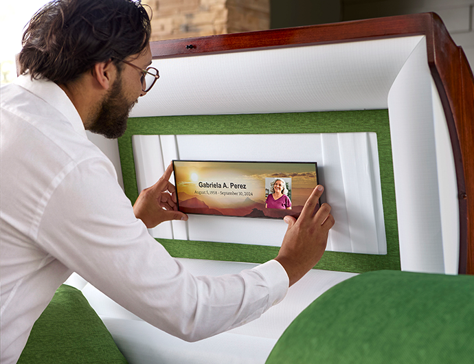 Man adding a memory frame to the inside of a casket